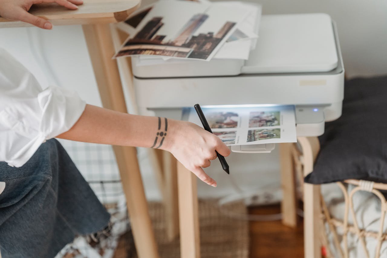 A woman using a stylus with a printer in a home office setting.